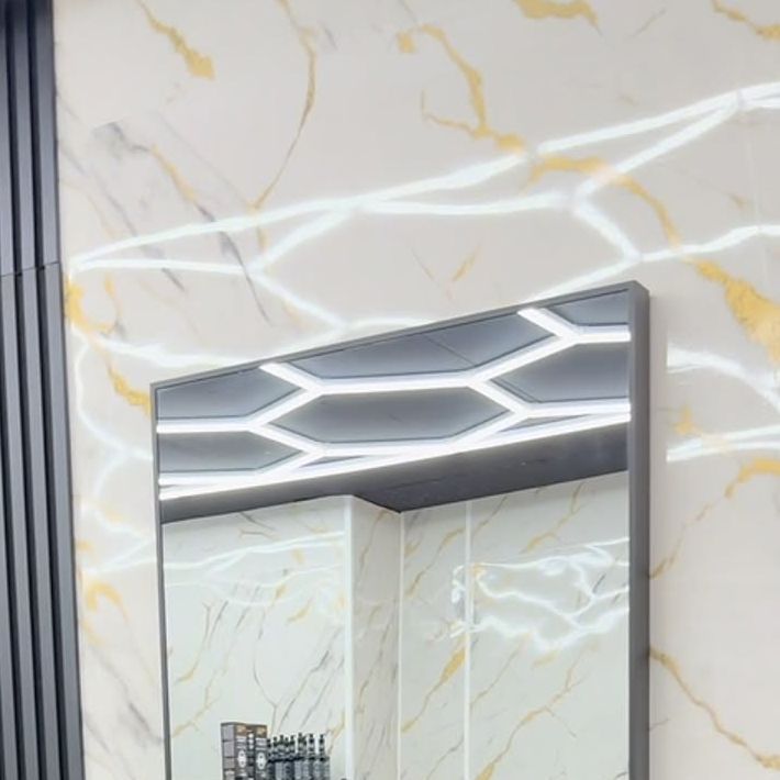 Wand in Marmor-Optik mit Goldadern und weißen LED-Lichtlinien, im Spiegel die leuchtende Wabendecke